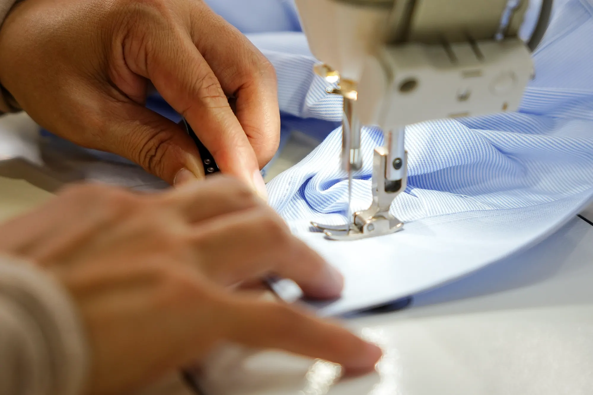 Hands guiding fabric through a sewing machine