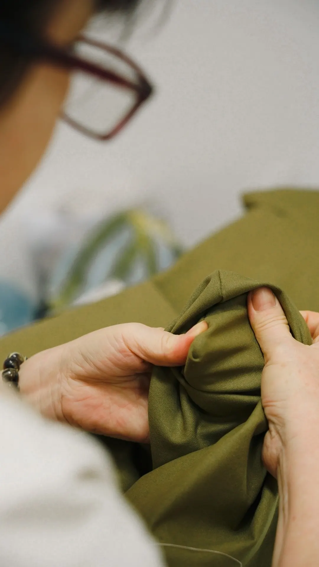 Hands checking the drape and finish of olive fabric